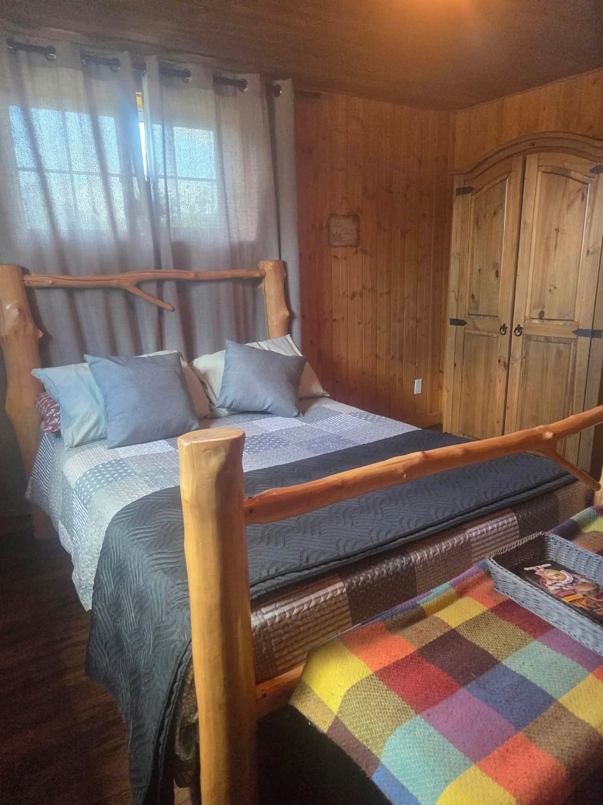 Lit en bois rond dans une chambre du gîte